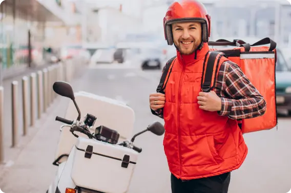 Repartidor de comida a domicilio sonriendo al lado de su moto.